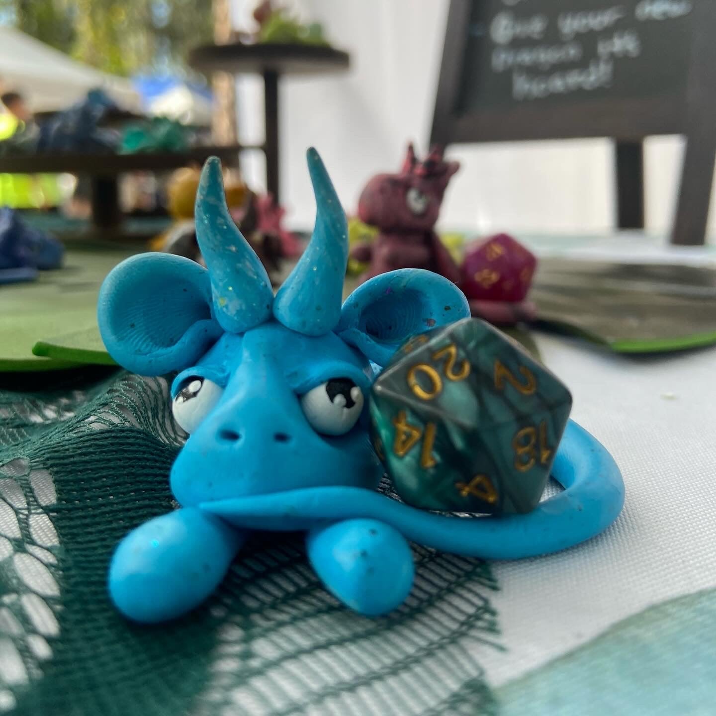 Blue dragon figurine holding a dice with a blurred background